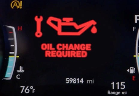 Automobile dashboard display indicates ‘oil change required” in bold red text