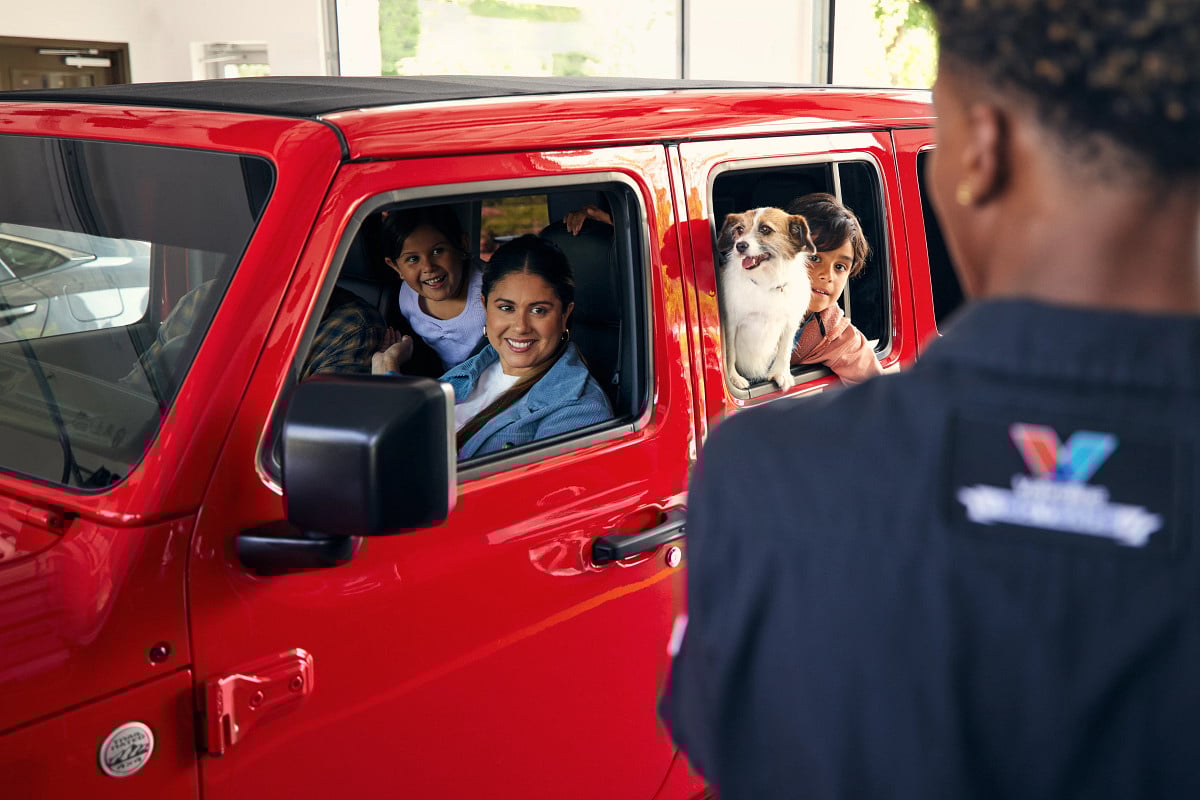 Certified Valvoline Instant Oil technician interacting with a family in a red vehicle