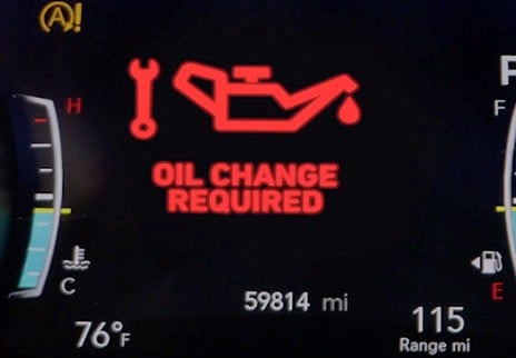 Automobile dashboard display indicates ‘oil change required” in bold red text