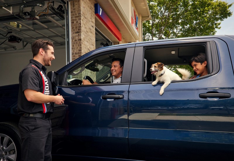 Valvoline Instant Oil Change technician greeting customers in a dark blue vehicle