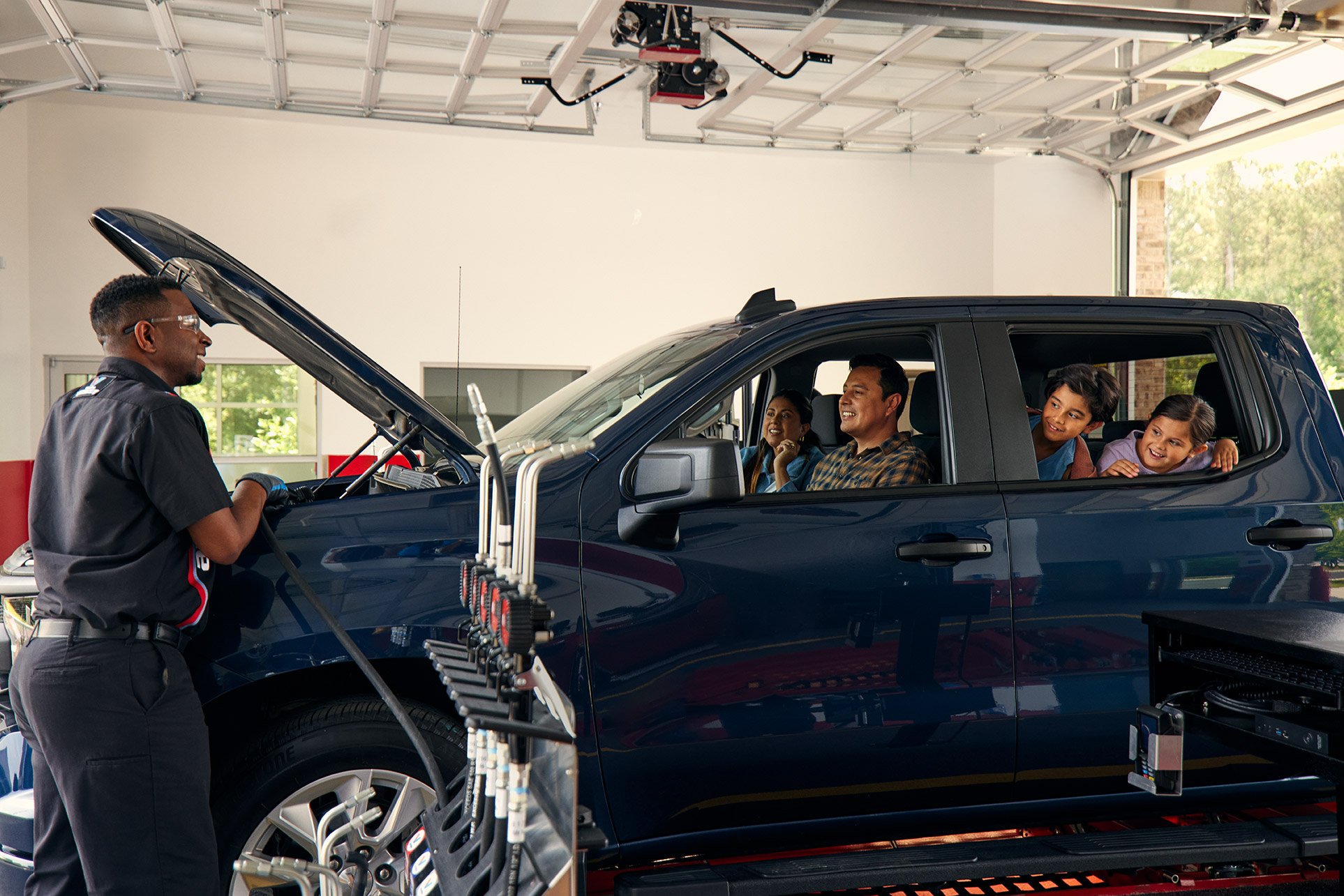 Certified Valvoline Instant Oil technician performing a service on a family's dark blue vehicle